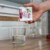 A hand is pouring yeast from a packet into a glass of water. Produktbild-Vorschau