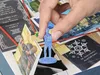 A hand is holding a blue game piece over a board game. Produktbild-Vorschau
