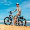 A man is sitting on an electric bicycle on a sandy beach with the ocean in the background. Produktbild-Vorschau