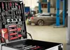 A tool trolley filled with tools in a workshop with a car in the background. Náhled obrázku produktu