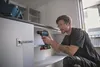 A man is using a cordless drill to assemble a cabinet. Voir les images du produit