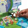 A hand is shown interacting with a My Little Pony playset, adjusting a tree accessory. The playset features miniature pony figures and various colorful elements. Produktbild-Vorschau