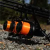 Close-up of fishing reels with orange fishing line, resting on gravel. Anteprima dell’immagine prodotto
