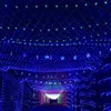 A tunnel decorated with blue and green lights, with snowflake-shaped lights scattered throughout. People are walking through the tunnel in the distance. Voir les images du produit