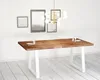 A dining table with white legs and a wooden top, set in a minimalist room with framed pictures on the wall and a modern chandelier. Produktbild-Vorschau