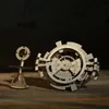 Two wooden mechanical puzzles, a perpetual calendar and a smaller abstract sculpture, are displayed on a wooden surface against a dark background with a faint map. Anteprima dell’immagine prodotto