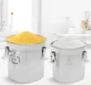 Two stainless steel canisters filled with food ingredients, one with yellow cornmeal and the other with white flour, are displayed in a bright, clean kitchen setting. Náhled obrázku produktu