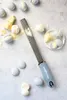 A grater with macarons and chocolate on a light gray surface. Náhled obrázku produktu