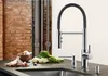 A modern kitchen sink area with a faucet, vegetables, and garlic on the countertop. Produktbild-Vorschau