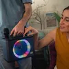 A man and a woman are holding a portable karaoke machine with colorful LED lights. Produktbild-Vorschau