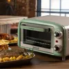 A vintage-style toaster oven is shown on a wooden table, surrounded by plates of food. Anteprima dell’immagine prodotto