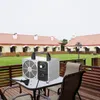An ozone generator sits on a table on a wooden deck, with buildings and greenery in the background. Produktbild-Vorschau