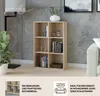 A light brown bookshelf with 6 compartments, filled with books and decorative items, is shown in a living room setting with a concrete wall and a sofa. Text overlays describe its features and ideal placement. Produktbild-Vorschau