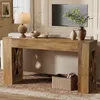A wooden console table with decorative X-shaped legs is placed in a living room setting, adorned with a lamp, decorative bowls, and vases. Podgląd zdjęcia produktu