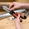 Hands holding a pair of metal shears, with metal pipes in the background. Anteprima dell’immagine prodotto