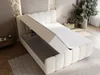 A white upholstered bed with its storage compartment open, revealing the interior. The bed is in a room with a textured wall and a plant in the background. Produktbild-Vorschau