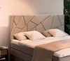 A bed with a geometric headboard and pillows. Produktbild-Vorschau