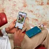 A person is holding a smartphone and a portable printer, with printed photos emerging from the printer. Anteprima dell’immagine prodotto