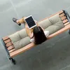 A woman sits on a wooden bench with cushions, using a tablet. Náhled obrázku produktu