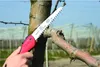 A person is using a folding saw to prune a tree branch. Podgląd zdjęcia produktu
