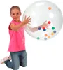 A young girl is kneeling and holding a large, clear activity ball filled with colorful smaller balls. Produktbild-Vorschau