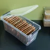 A clear plastic storage box filled with small brown paper packets, likely containing spices or tea, is shown with its lid open. Anteprima dell’immagine prodotto