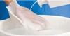 A hand wearing a disposable wash glove is being rinsed under a stream of water from a bottle, over a white basin. Anteprima dell’immagine prodotto