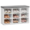 A white shoe bench with a gray upholstered top, filled with various pairs of women's shoes. Náhled obrázku produktu
