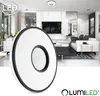 A modern living room with a ceiling lamp in the foreground and a living room scene in the background. Produktbild-Vorschau