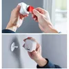 Hands are shown installing a white motion sensor. The top image shows a red tab being removed from the sensor. The bottom image shows the sensor being attached to a wall mount. Produktbild-Vorschau