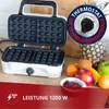 A waffle maker is shown open, with a selection of fruits and a bowl of jam in the foreground, set against a wooden background. Produktbild-Vorschau