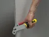 A person's hand holding a drywall panel carrier tool against a drywall panel. Náhled obrázku produktu