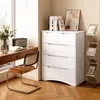 A white dresser with drawers is placed next to a wooden desk with a chair in a room with wooden floors and a window. Podgląd zdjęcia produktu