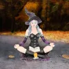 Hexe in meditativen Haltung. Sie trägt spitzen Hexenhut und eng anliegendes Kleid mit Schnürung. Produktbild-Vorschau