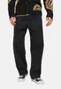 A person wearing black jeans and a black cardigan with a patterned design. Produktbild-Vorschau