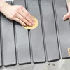 A person's hands are shown sanding a gray, slatted surface, possibly a bath mat or outdoor furniture. Anteprima dell’immagine prodotto