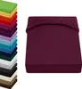 A stack of folded fitted sheets in various colors is shown on the left, with a single fitted sheet in bordeaux color displayed prominently on the right. Produktbild-Vorschau