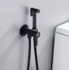 A black bidet sprayer set mounted on a light gray wall next to a white toilet. Podgląd zdjęcia produktu