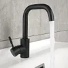 A black kitchen faucet with water running into a white sink, with a tiled wall in the background. Produktbild-Vorschau