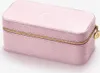 A pink jewelry box with a gold zipper and a gold charm. Voir les images du produit