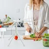 A person is chopping vegetables in a kitchen next to a white pasta drying rack. Produktbild-Vorschau