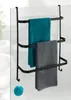 A black metal towel rack with three bars, holding two towels (one teal, one gray), hanging on a glass shower door. A teal pom-pom is visible on the floor. Náhled obrázku produktu