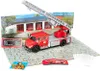A model fire truck with a ladder, set against a backdrop of a fire station and a paved area. Produktbild-Vorschau