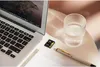 A micro SD card is placed next to a laptop, a glass of water, and a pen on a desk. Náhled obrázku produktu