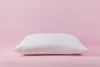 A white pillow is centered on a pink background. Produktbild-Vorschau