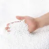 A hand holding a pile of small white polystyrene beads. Anteprima dell’immagine prodotto