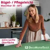 A woman is placing a dark green tablecloth on a table in a kitchen setting. Produktbild-Vorschau