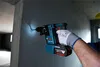 A person wearing a glove is using a Bosch rotary hammer drill to make a hole in a concrete wall. Produktbild-Vorschau