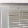 A close-up view of the top section of cream-colored horizontal blinds mounted in a white window frame. Produktbild-Vorschau