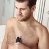A man is grooming his chest with an electric shaver in a bathroom setting. Podgląd zdjęcia produktu